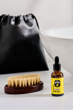 Bottle of liquid soap with a brush on a bathroom counter next to a sink.